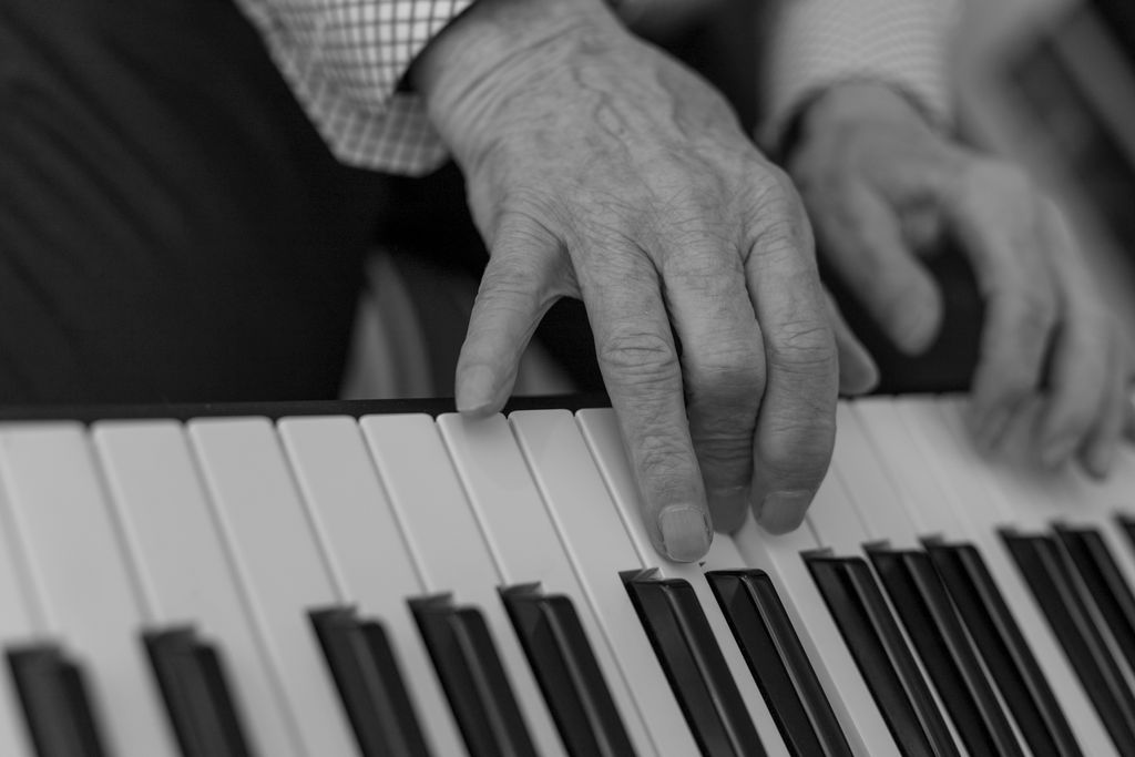 Black and white photograph focusing on hands playing a piano, highlighting technique and musical expression.